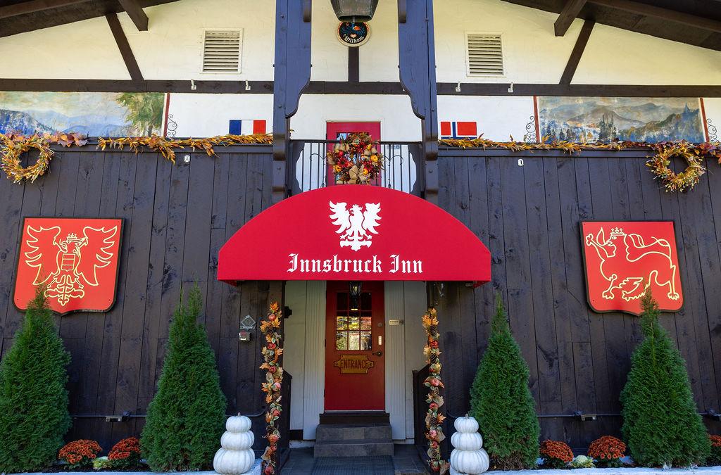 Red awning entrance to Innsbruck Inn with decorative wreaths and greenery.