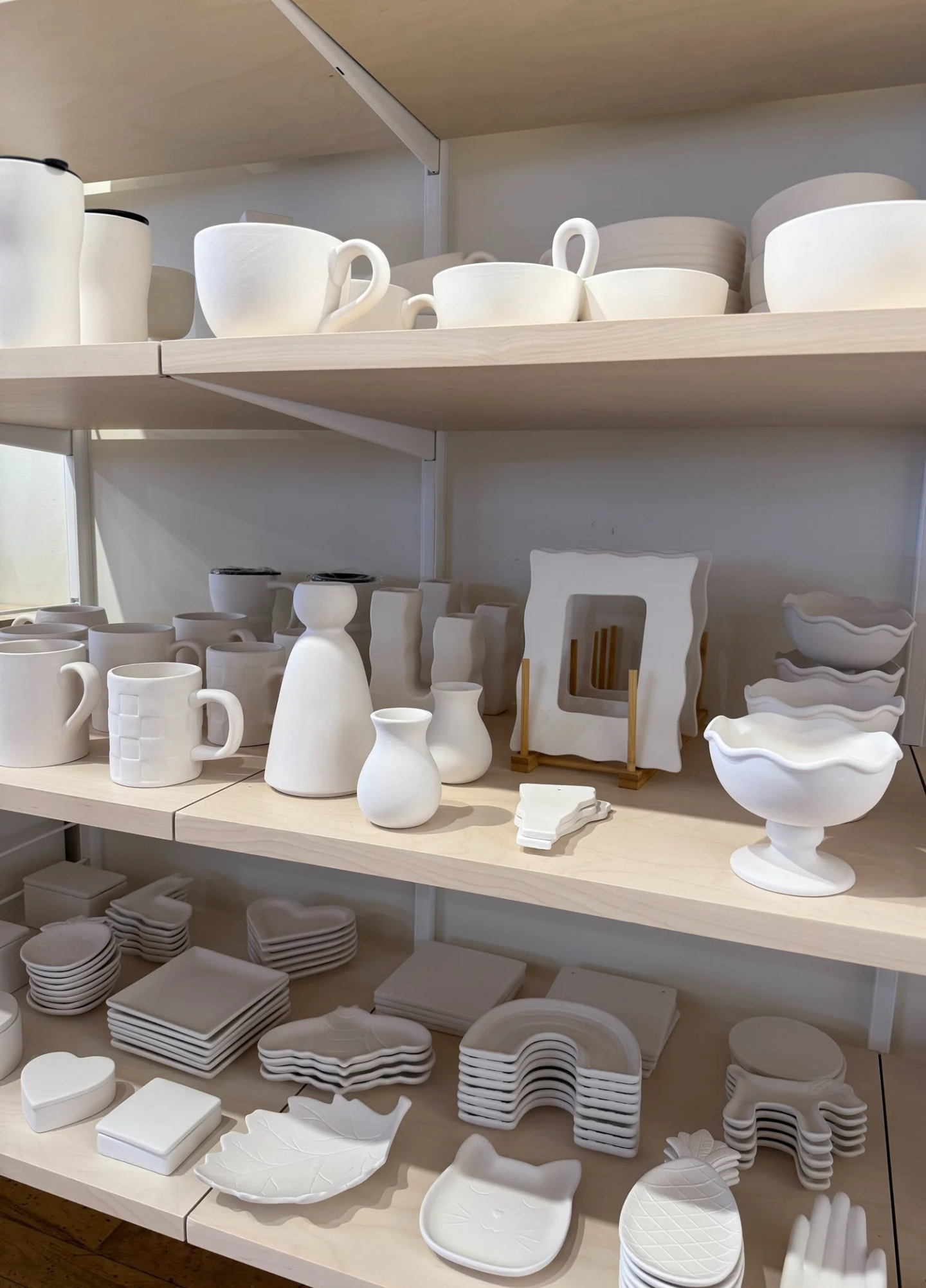 Ceramic shelf with white pottery, vases, cups, and decorative items.