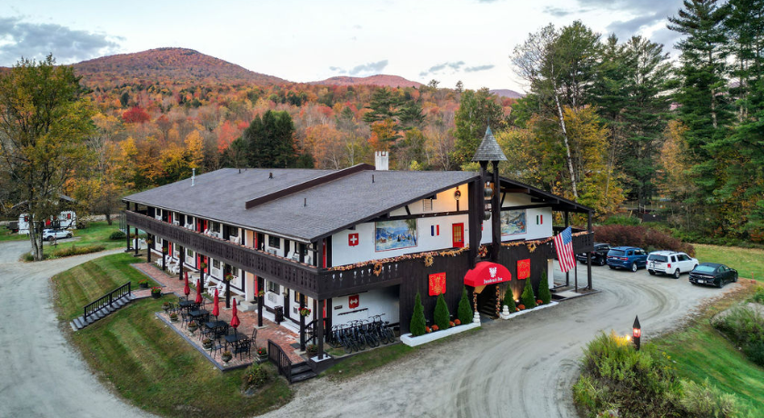 A lodge in autumn with colorful trees and mountains in the background.