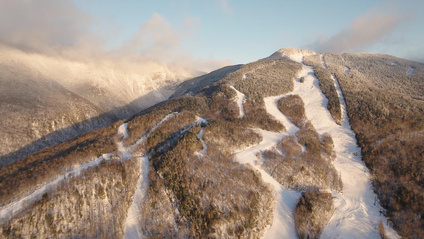 Snow-covered mountain with ski trails and a clear sky.