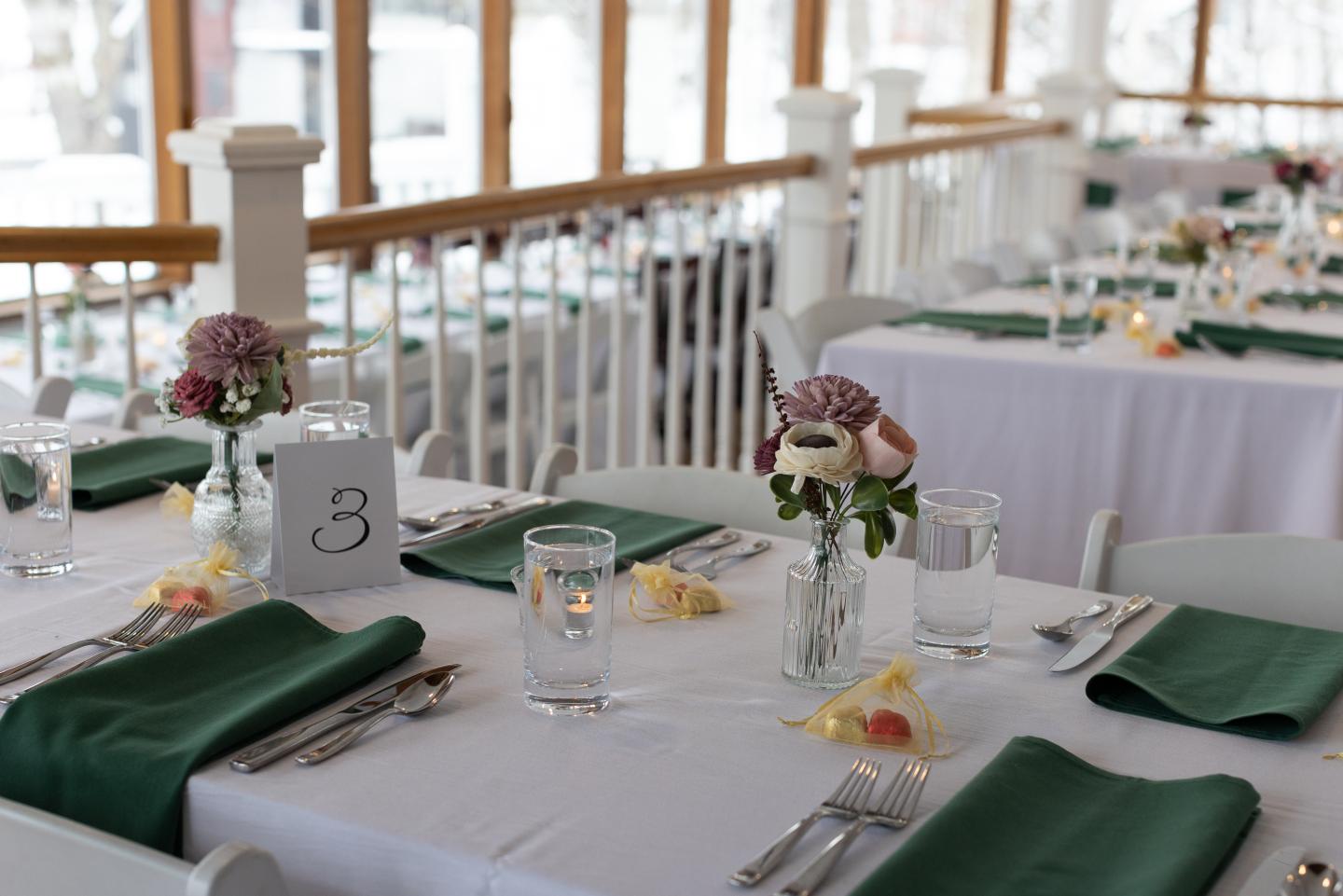 Elegant table setting with green napkins and floral centerpieces.