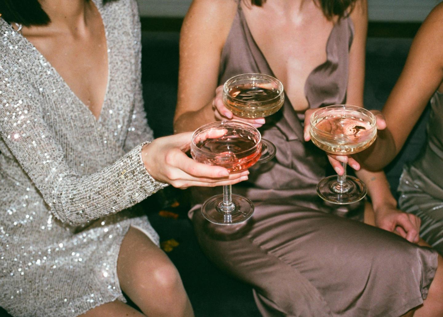 Women in elegant dresses clinking glasses of champagne.