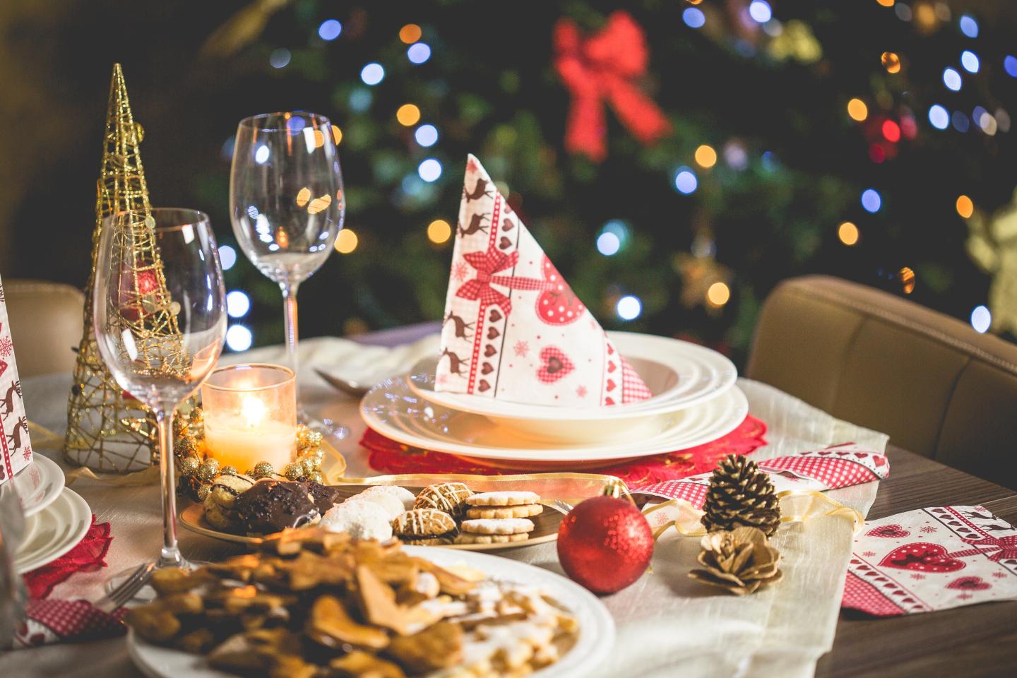 Festive table setting with cookies, candle, and Christmas tree in the background.