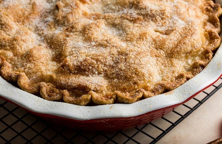 Golden, sugar-topped pie in a red dish on a cooling rack.