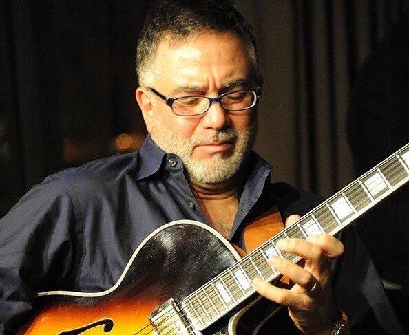 Guitarist with glasses playing an electric guitar focused and immersed in music.