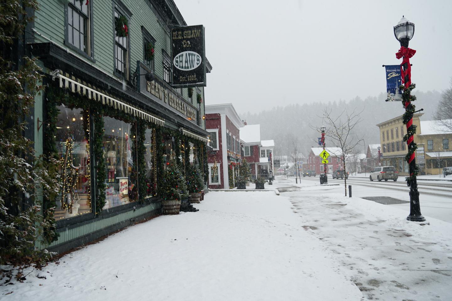 Snowy street with festive shopfront and holiday decorations.