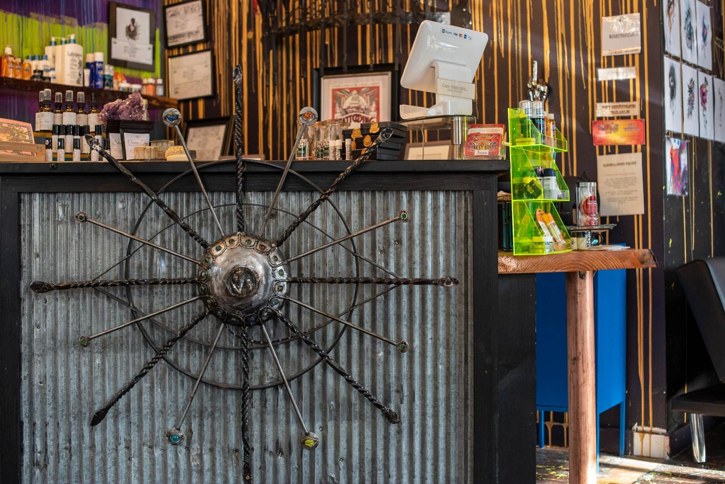 Corrugated counter with artwork and green bottles, colorful backdrop.