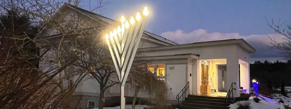 Glowing menorah outside a building at dusk.