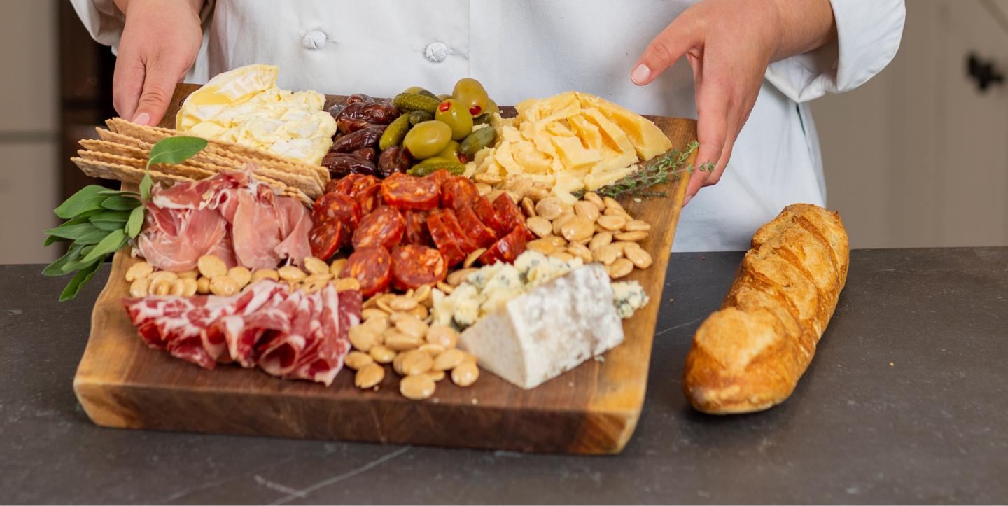 Charcuterie board with meats, cheeses, olives, and bread on a countertop.