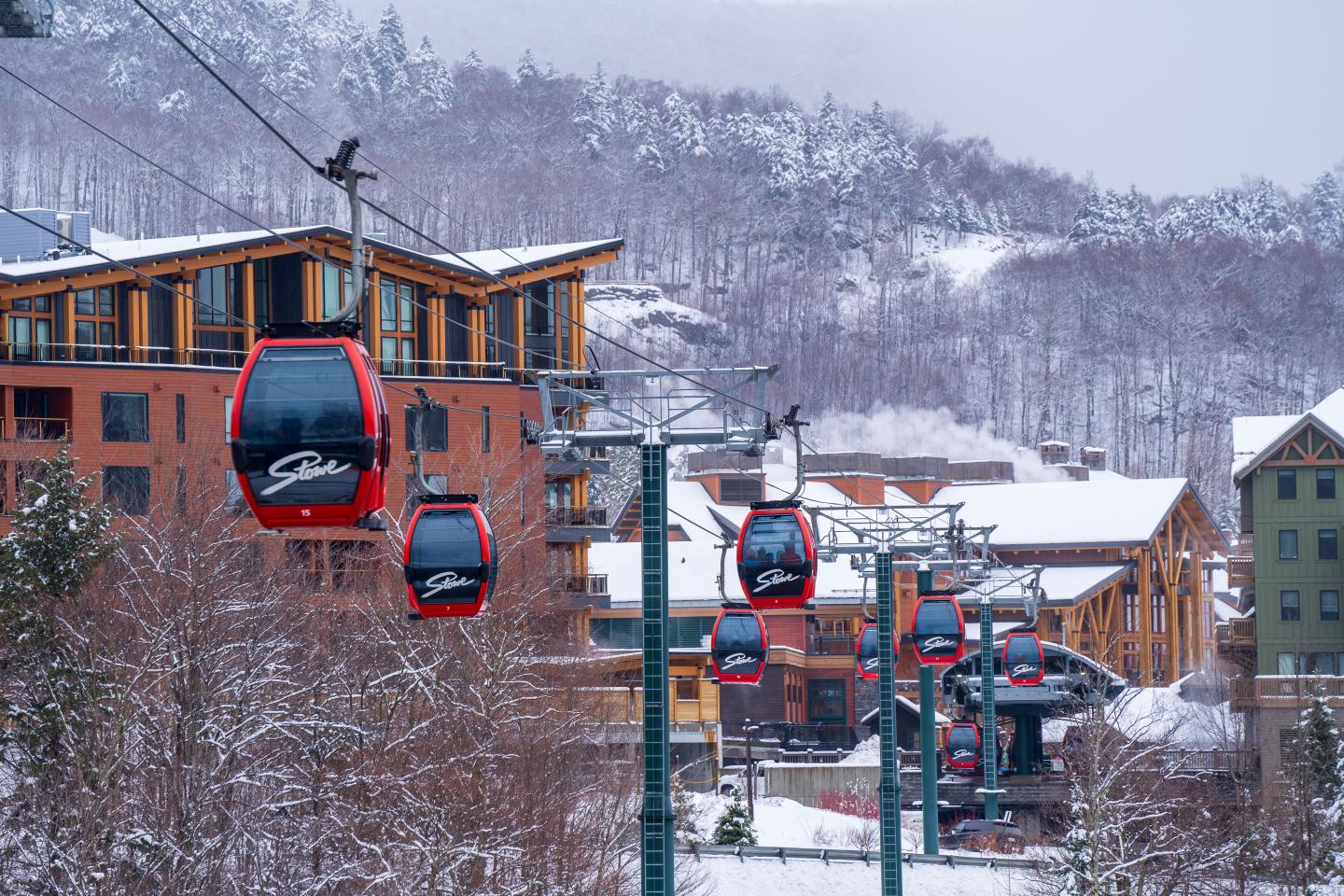 Red gondolas in a snowy mountain village setting.