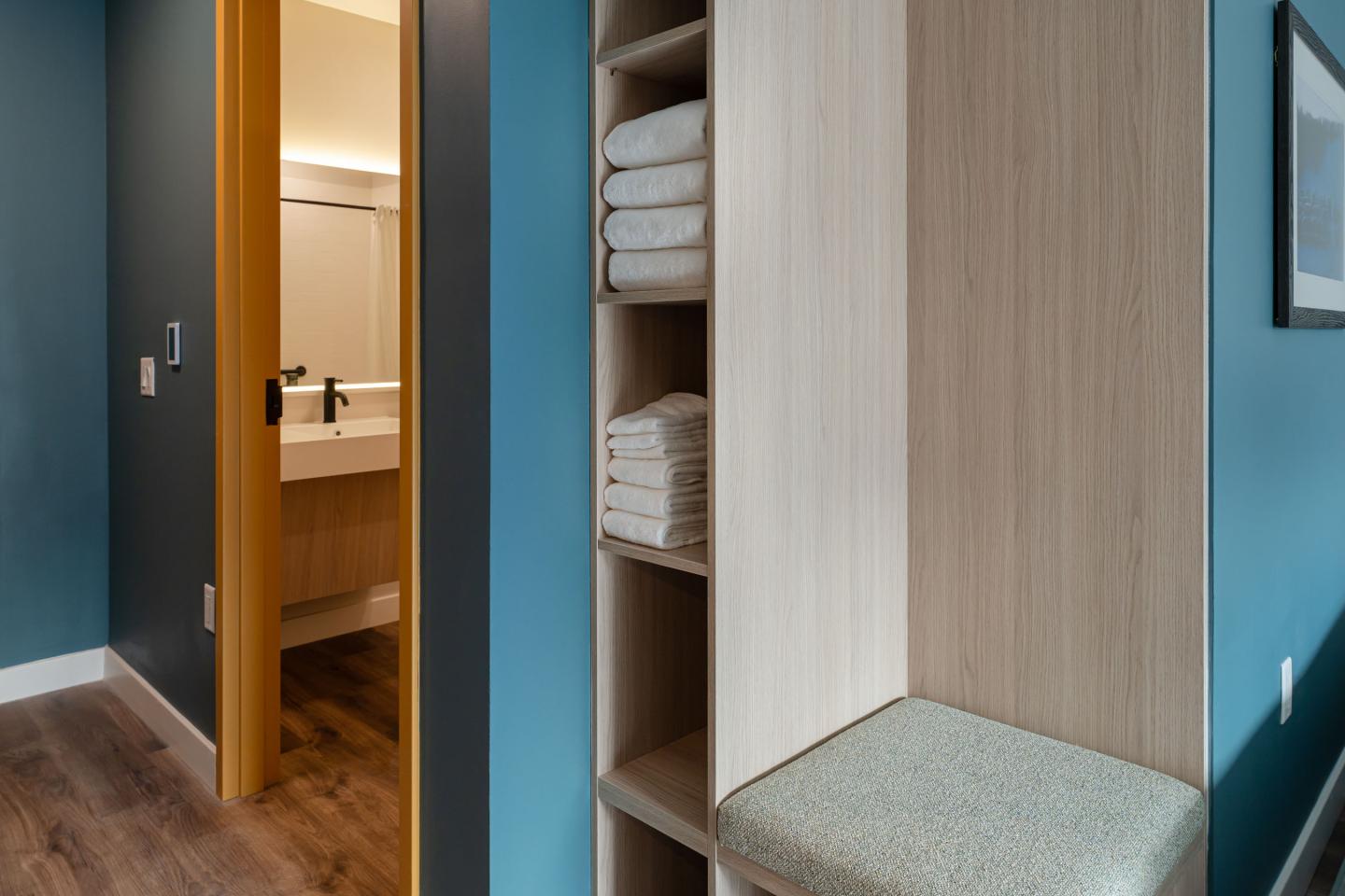 Shelf with neatly stacked towels beside an open bathroom door.