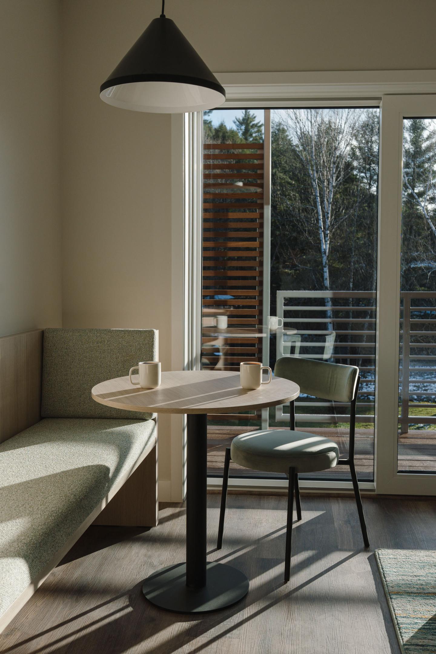 Cozy cafe corner with table, chairs, and large window.