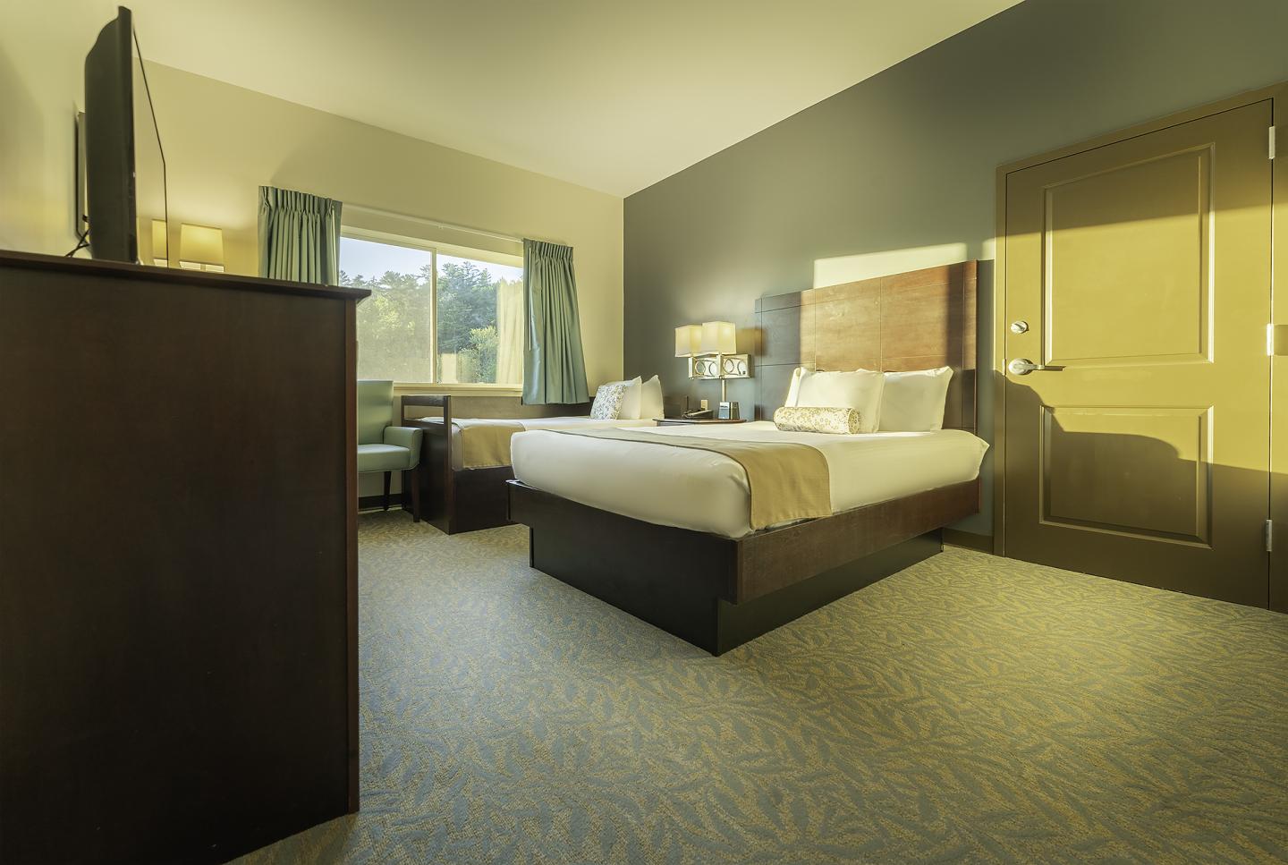 Cozy hotel room with a bed, TV, and large window.