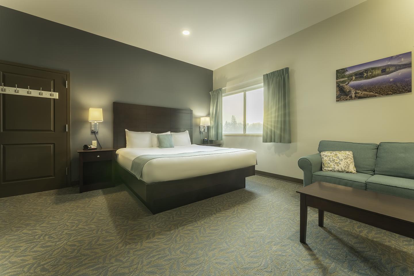 Hotel room with a bed, sofa, coffee table, and soft lighting.