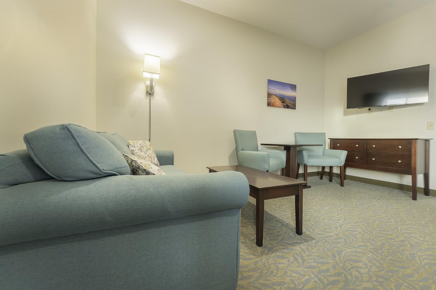 Cozy living room with blue sofa, chairs, TV, and wall art.