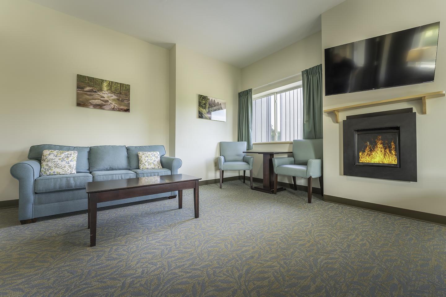 Cozy living room with sofa, armchairs, TV, and fireplace.