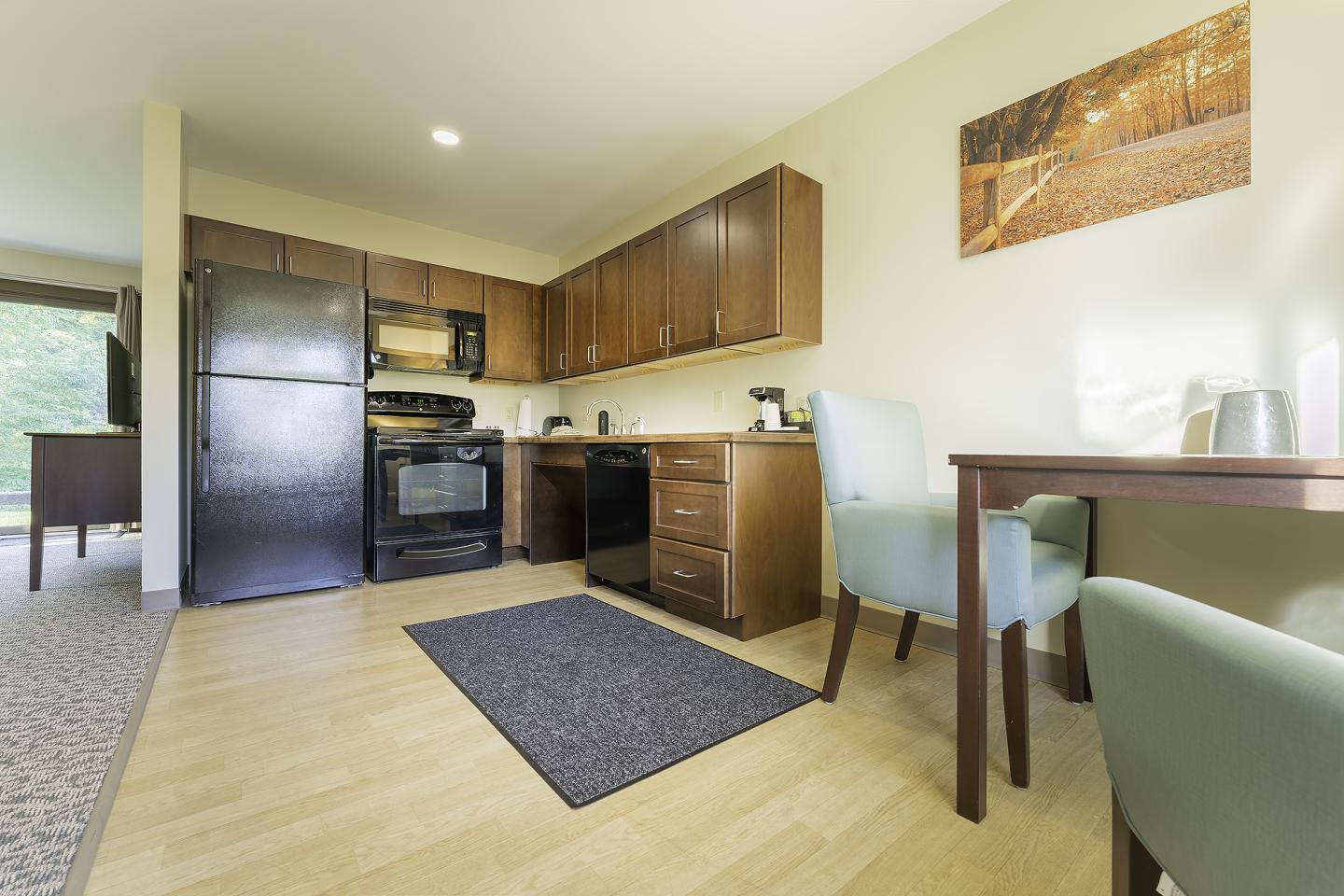 Cozy kitchen with wooden cabinets, black appliances, dining table, and chairs.