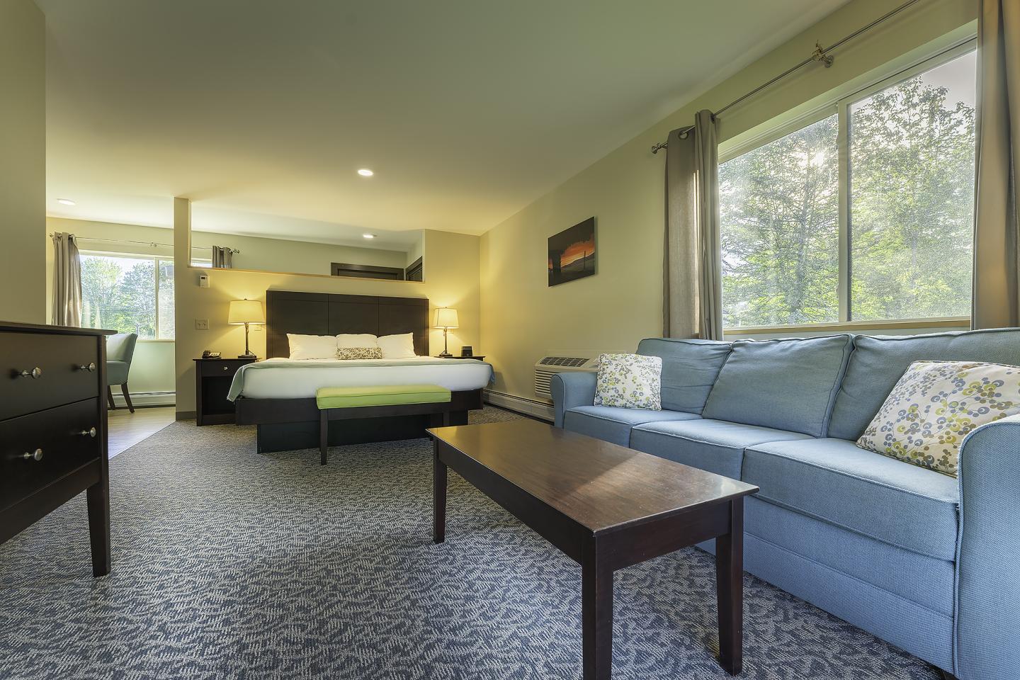 Spacious hotel room with bed, sofa, and large window.