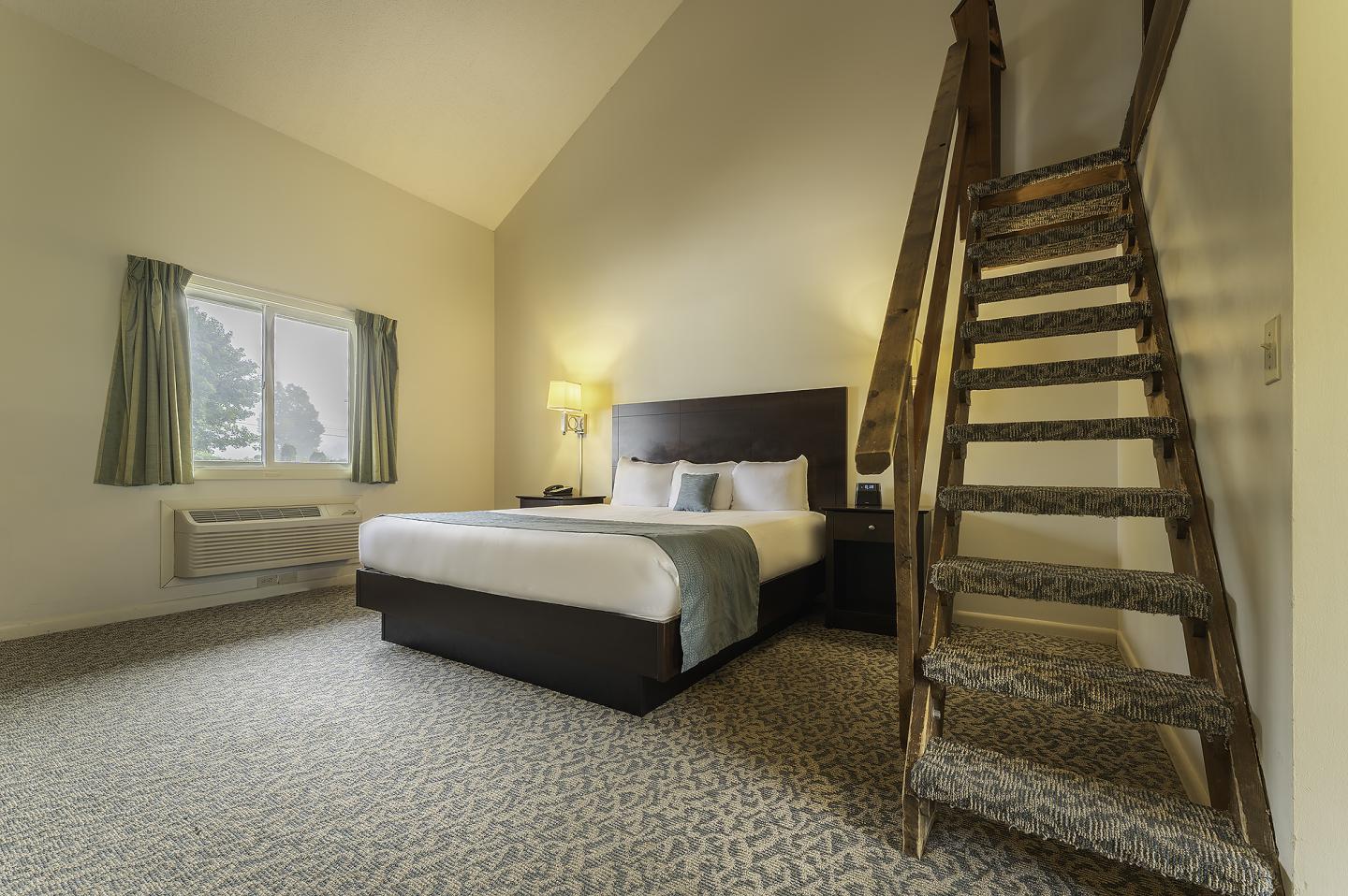 Cozy bedroom with a bed, stairs, window, and soft lighting.