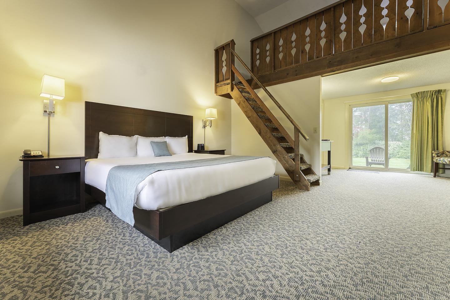 Spacious room with a bed, staircase, and large window.