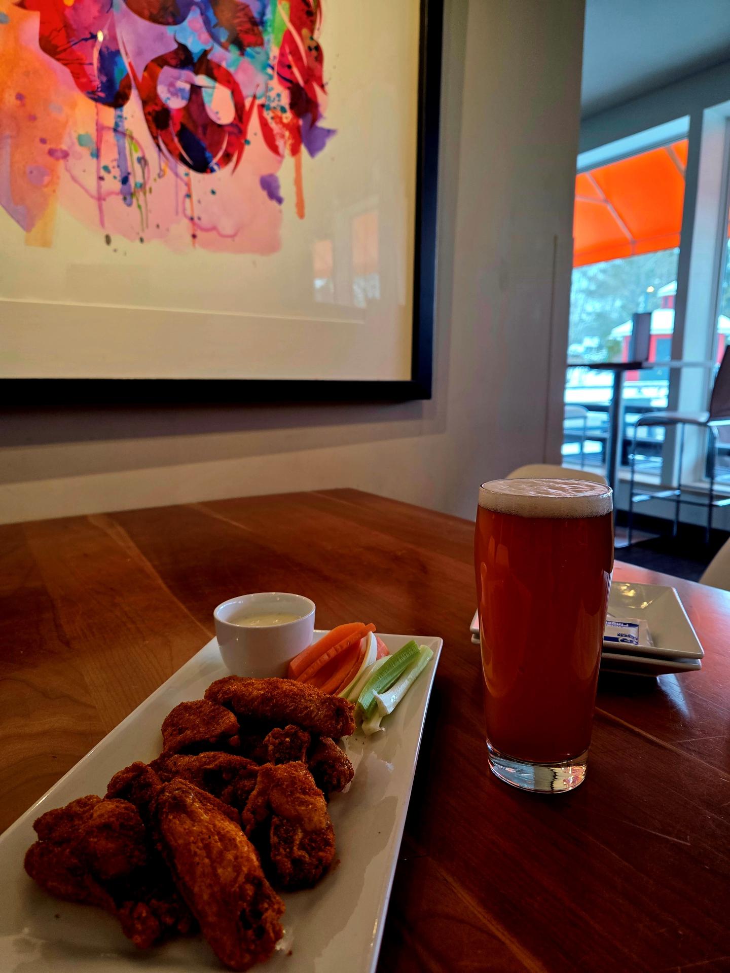 Fried chicken with dip and beer on a table near abstract art.
