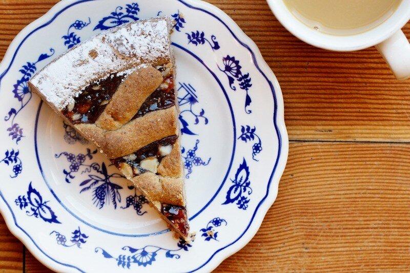Pie slice on a blue-patterned plate next to a cup of coffee on a wooden table.
