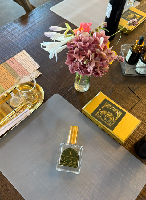 Perfume bottle on table with flowers and items.