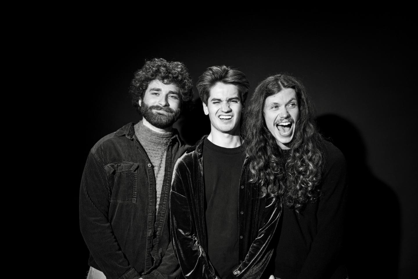 Three people smiling in a black and white portrait.