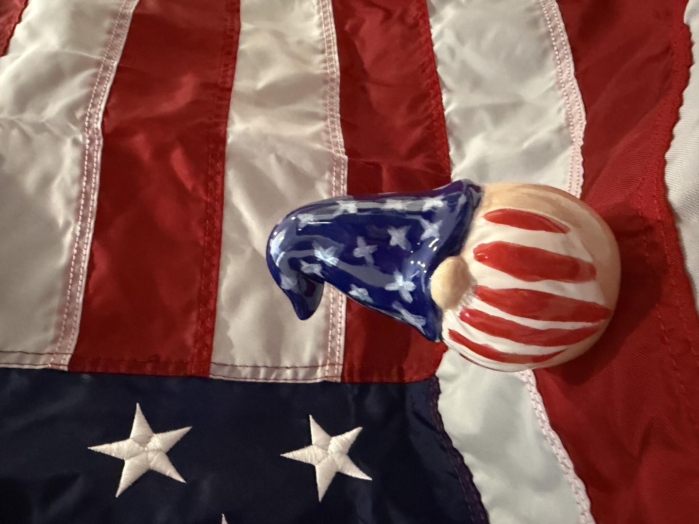 Ceramic gnome with flag hat on American flag background.