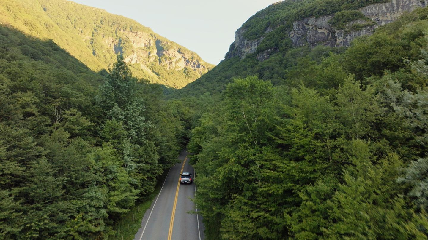 Car driving through a lush, green mountain valley.