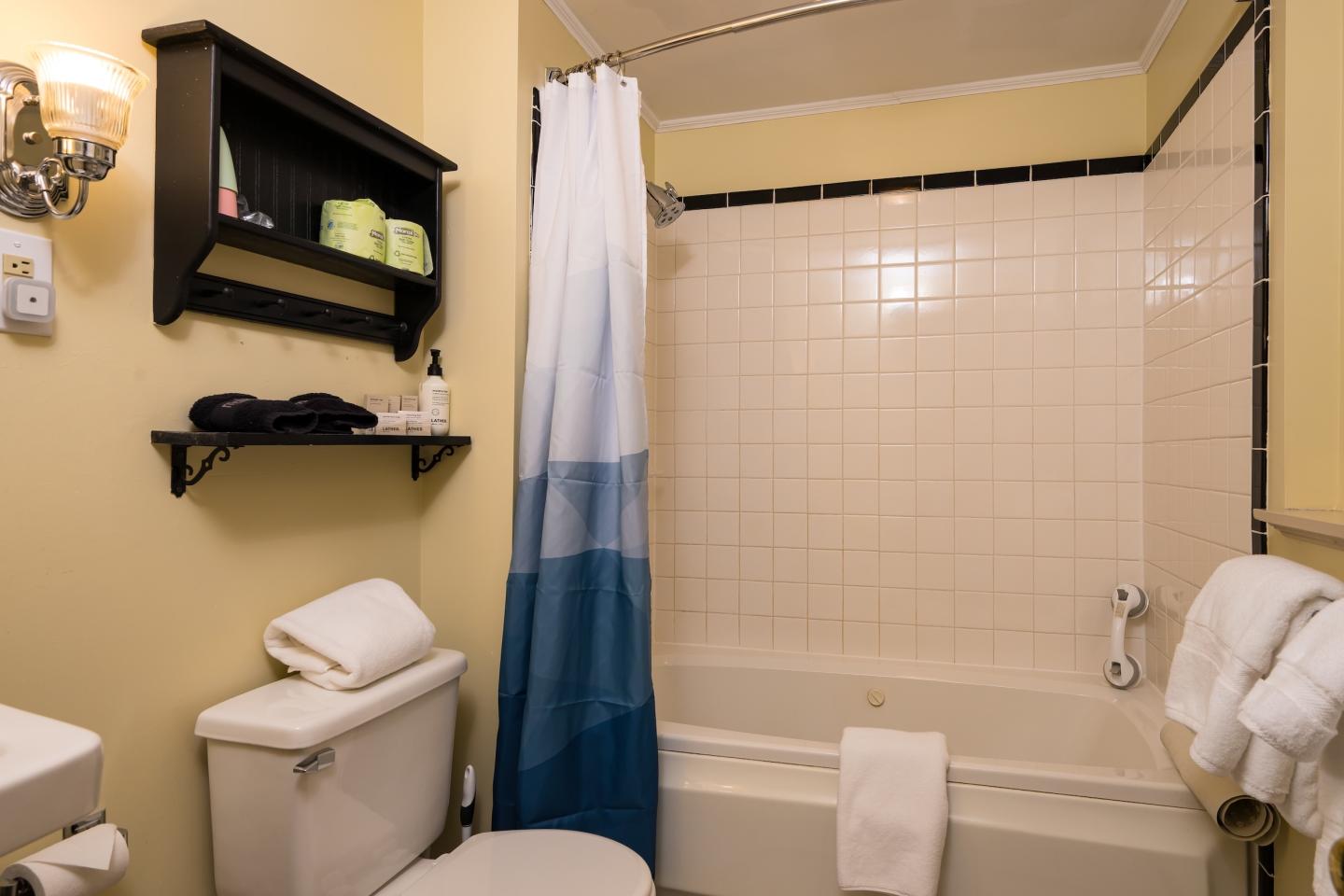 Cozy bathroom with a tub, white tiles, and blue gradient shower curtain.