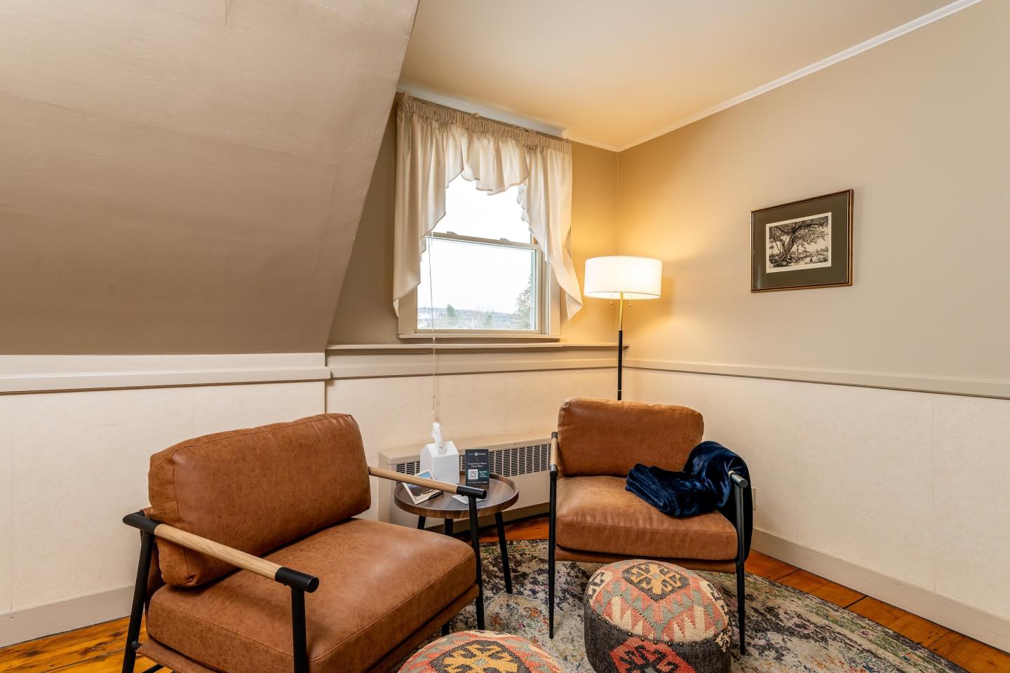 Cozy room with two brown chairs, a round table, and a window.