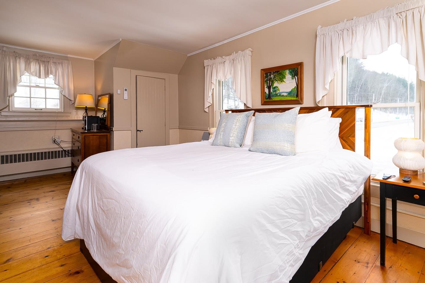 Cozy bedroom with a large bed, wooden floor, and soft lighting.