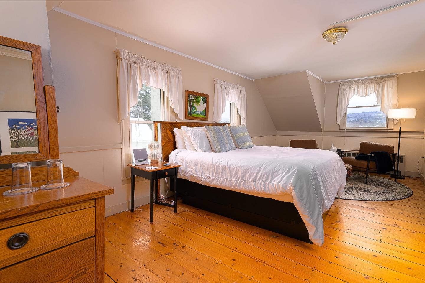 Cozy bedroom with a white bed and warm wooden furniture.