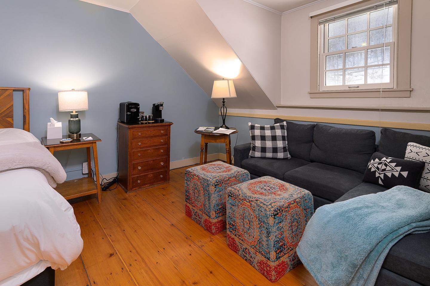 Cozy bedroom with blue walls, wooden floor, sofa, bed, and lamps.