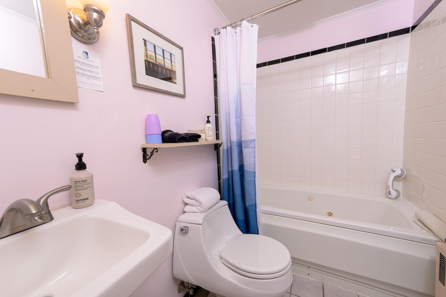 Bathroom with a sink, toilet, and bathtub with a blue shower curtain.
