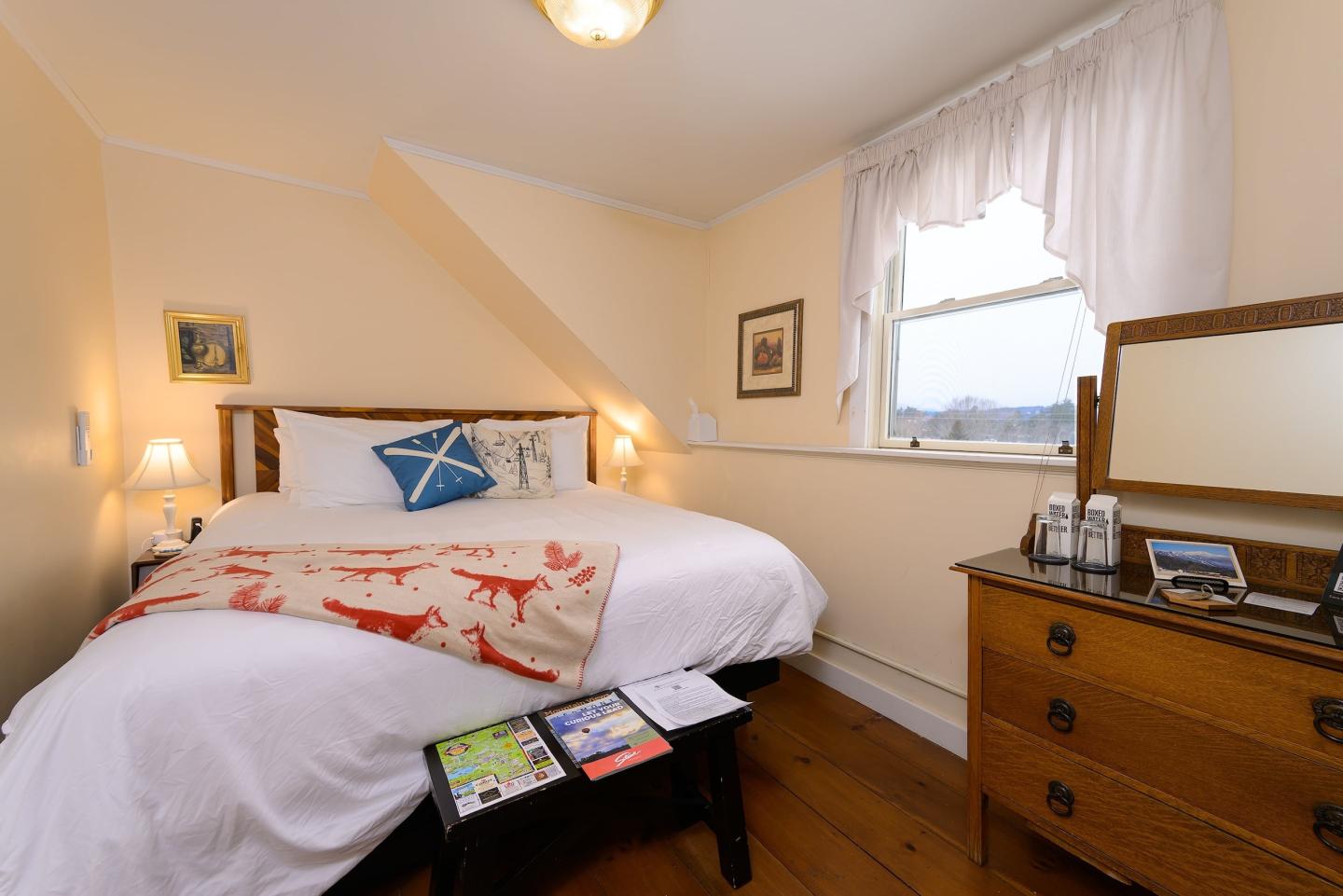 Cozy bedroom with a large bed, wooden dresser, and window.