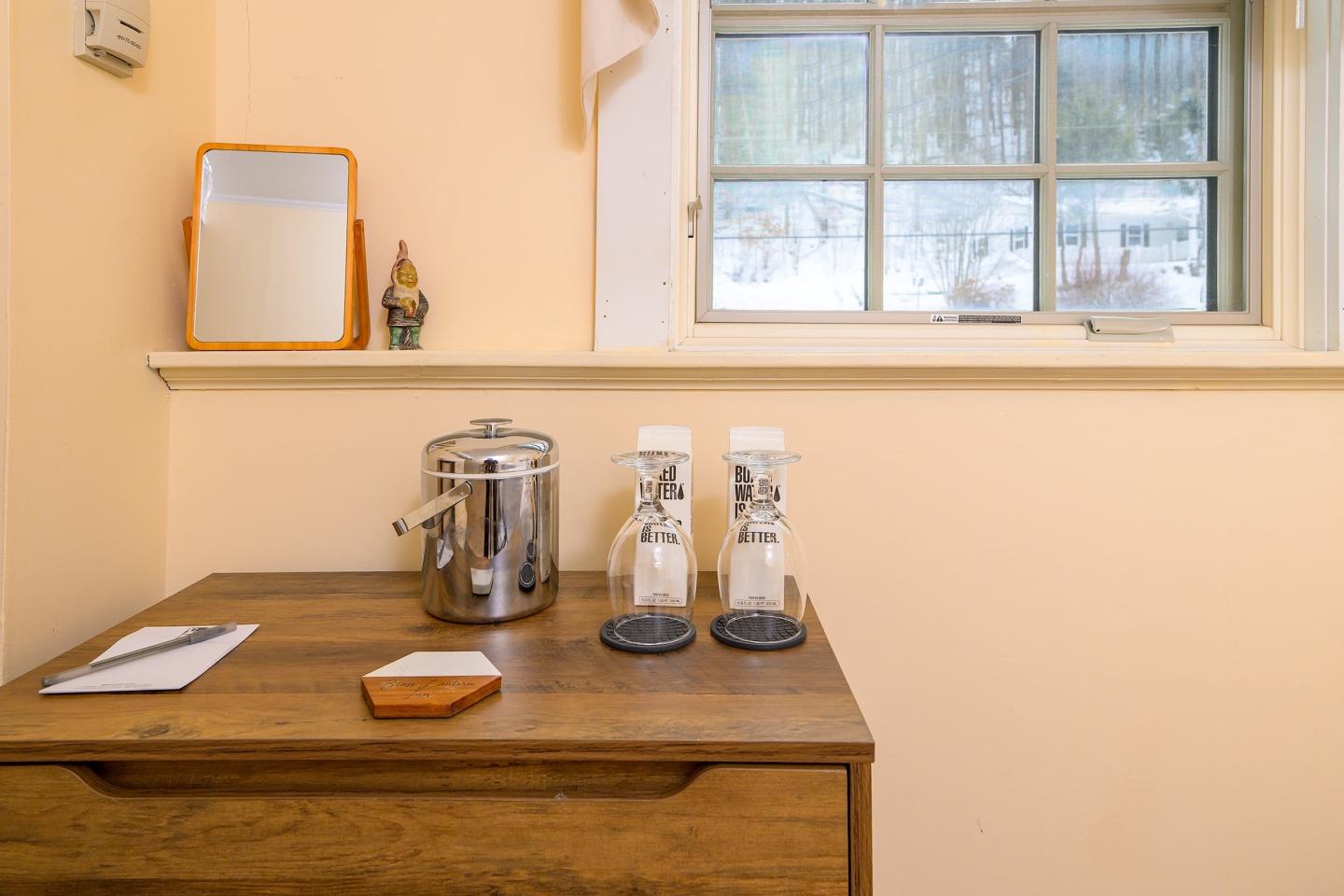 Counter with a coffee pot, two glasses, notepad, and window view.