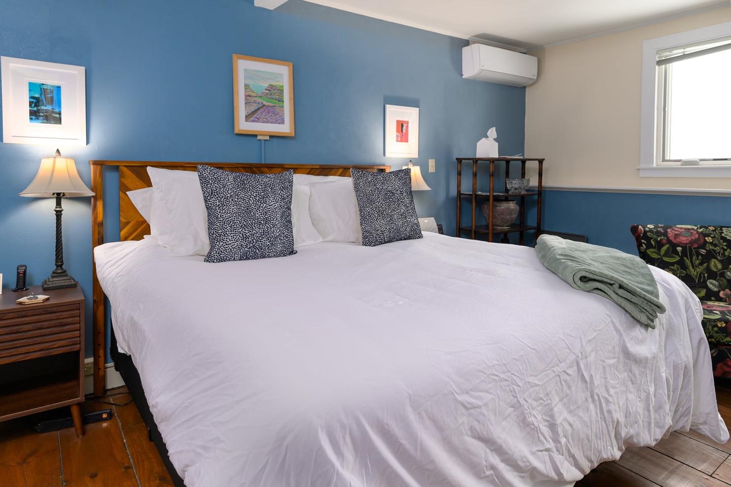 Bedroom with a large bed, blue walls, and framed art.