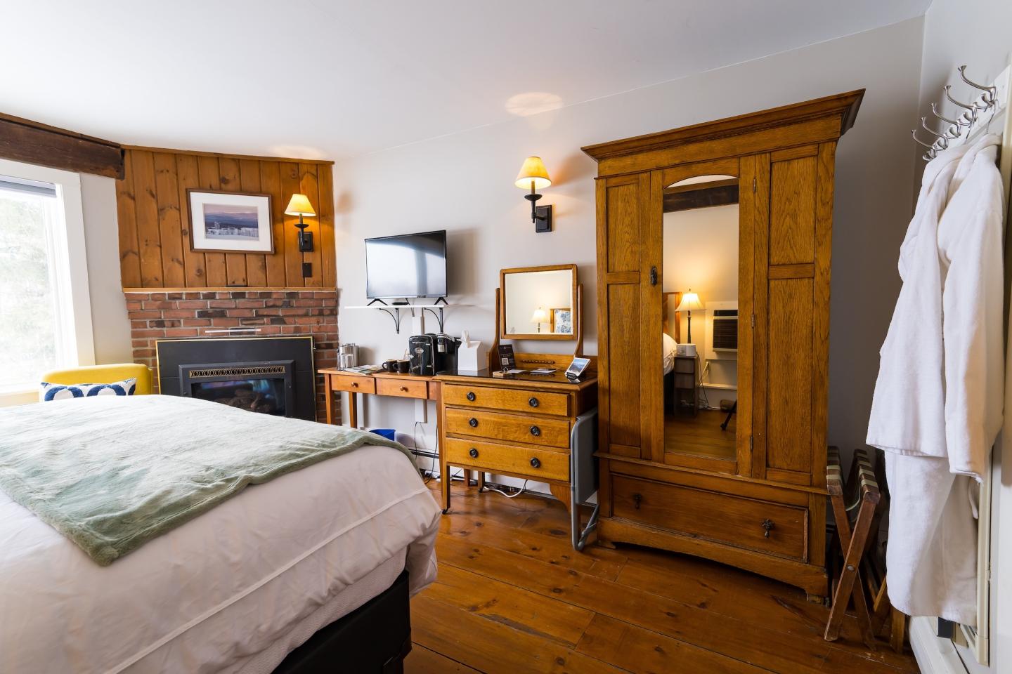 Cozy bedroom with wooden furniture, a fireplace, and soft lighting.