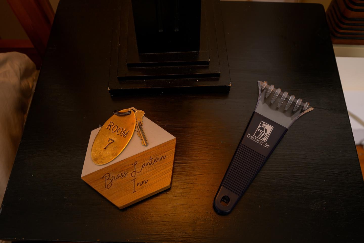 Key with wooden tag and a scraper tool on a dark table.