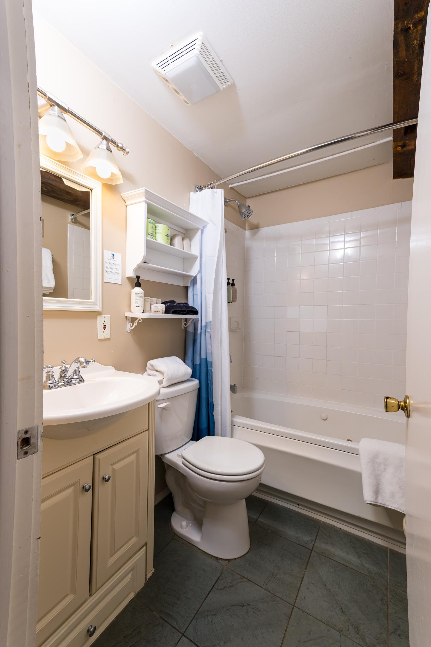 Compact bathroom with a sink, toilet, and bathtub, white and beige tones.