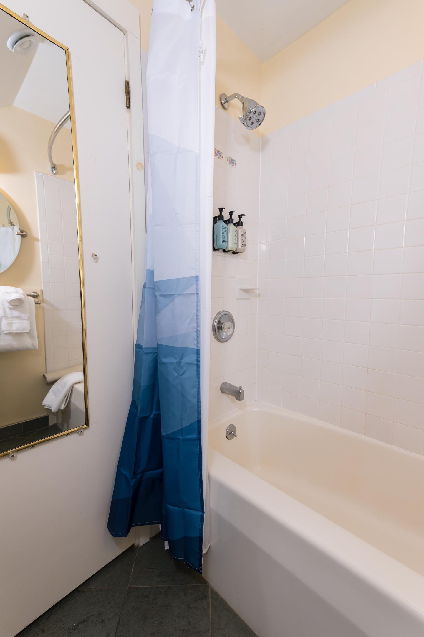 Bathtub with a blue gradient shower curtain and toiletries on the wall.