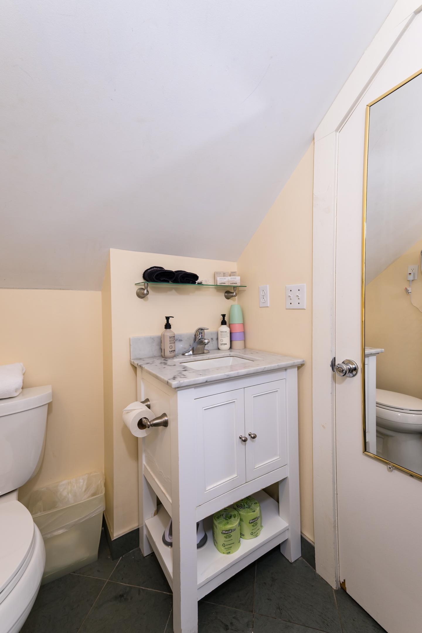 Small bathroom with a toilet, sink, and mirror.