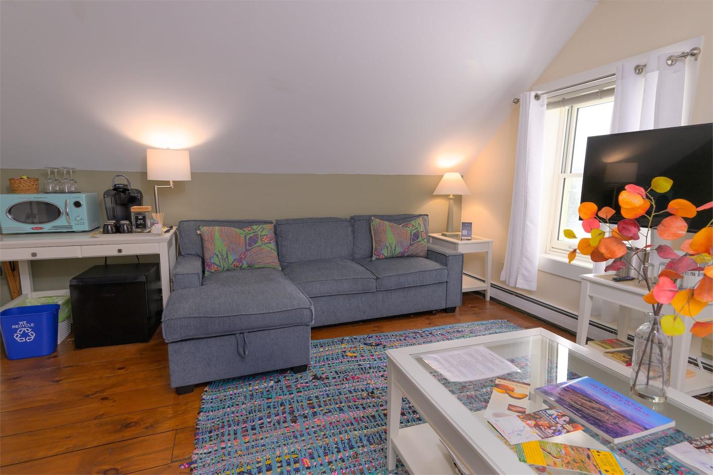Cozy living room with a blue sofa, TV, and colorful decor.