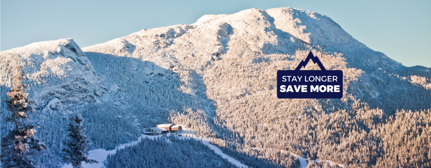 Snow-covered mountain with trees and a ski lodge on a bright day.
