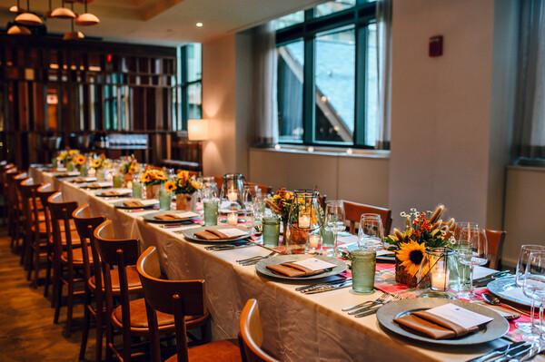 Elegant dining table set with sunflowers, candles, and tableware in a cozy, well-lit room.