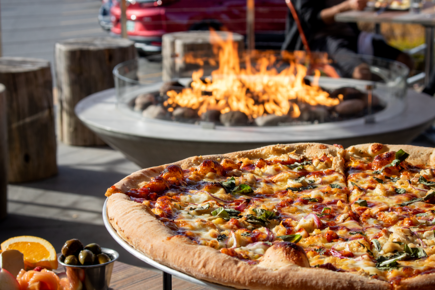 Pizza on a table near a fire pit outdoors.