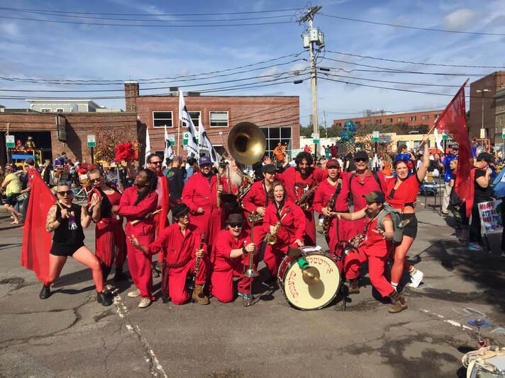 Marching band in red uniforms posing on a street with instruments.
