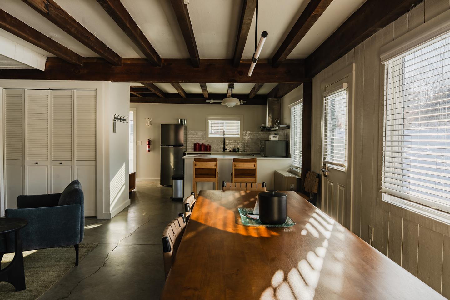 Sunlit kitchen and dining area with wooden beams and modern furniture.